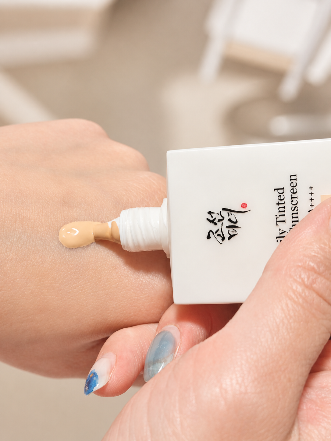 Beauty of Joseon Daily Tinted Fluid Sunscreen being dispensed onto the back of a hand