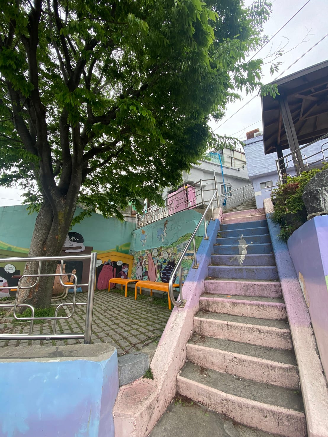 A staircase painted pastel pink, purple, and blue with a cat mural running up the steps