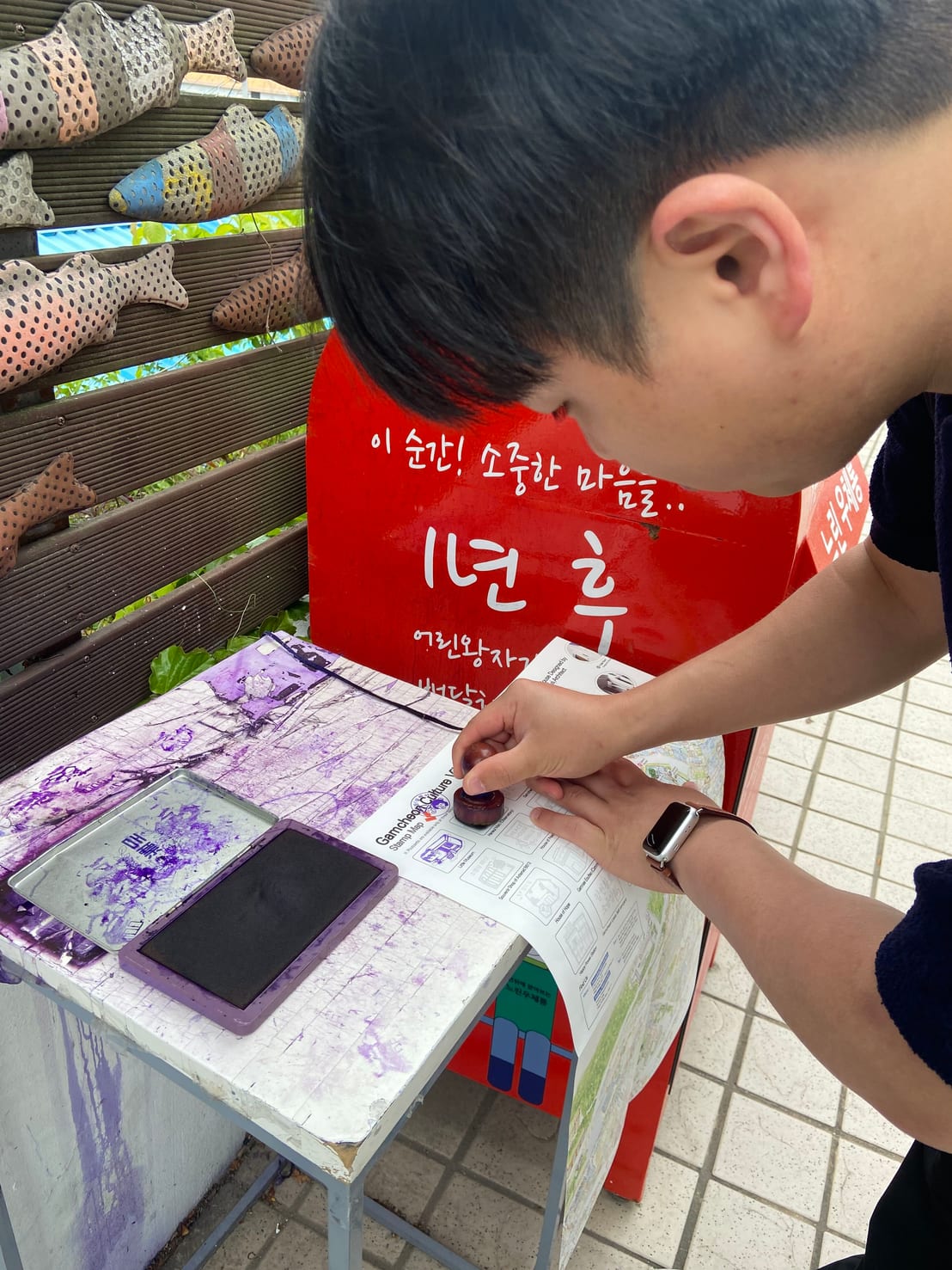 Stamping the Gamcheon Culture Village stamp map at one of the purple ink stations along the route