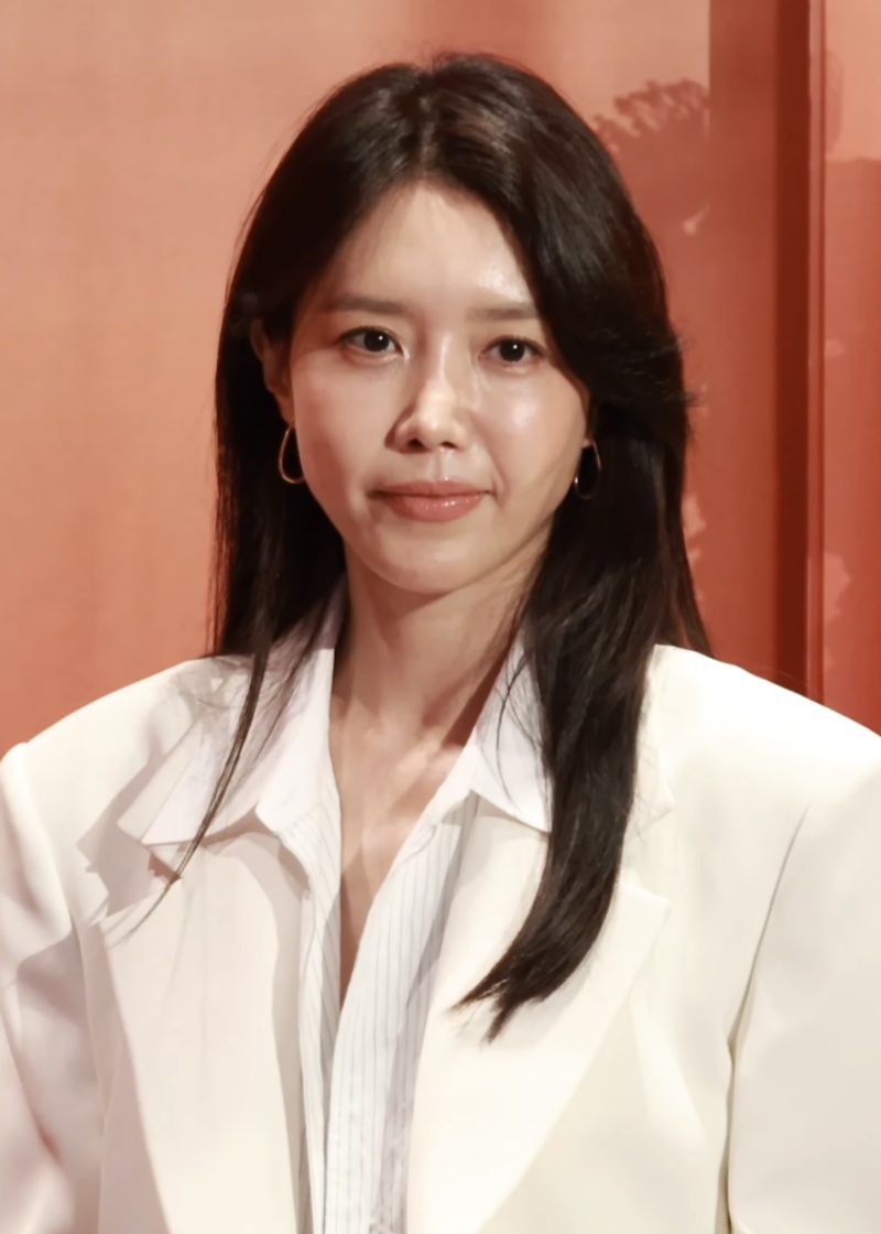Actress Chae Jung-an in a white blazer and striped shirt with small gold hoop earrings