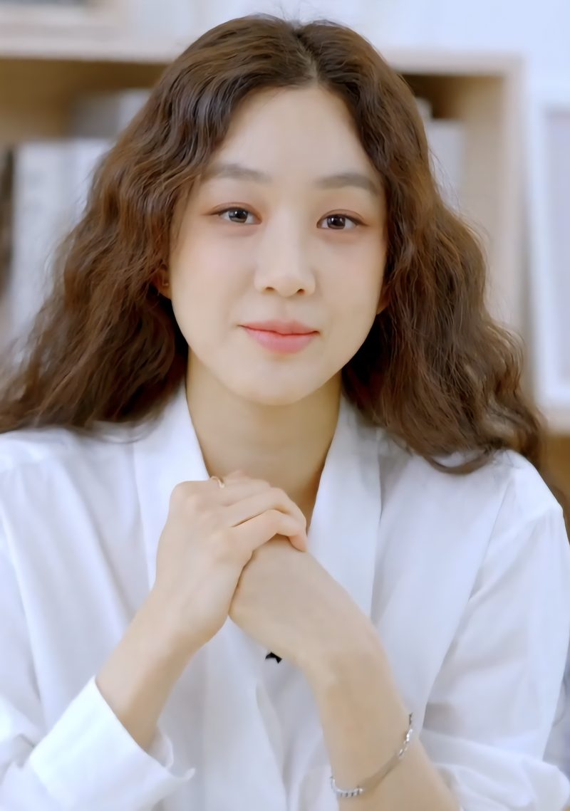 Actress Jung Ryeo-won with long wavy hair in a white shirt and thin silver bracelet