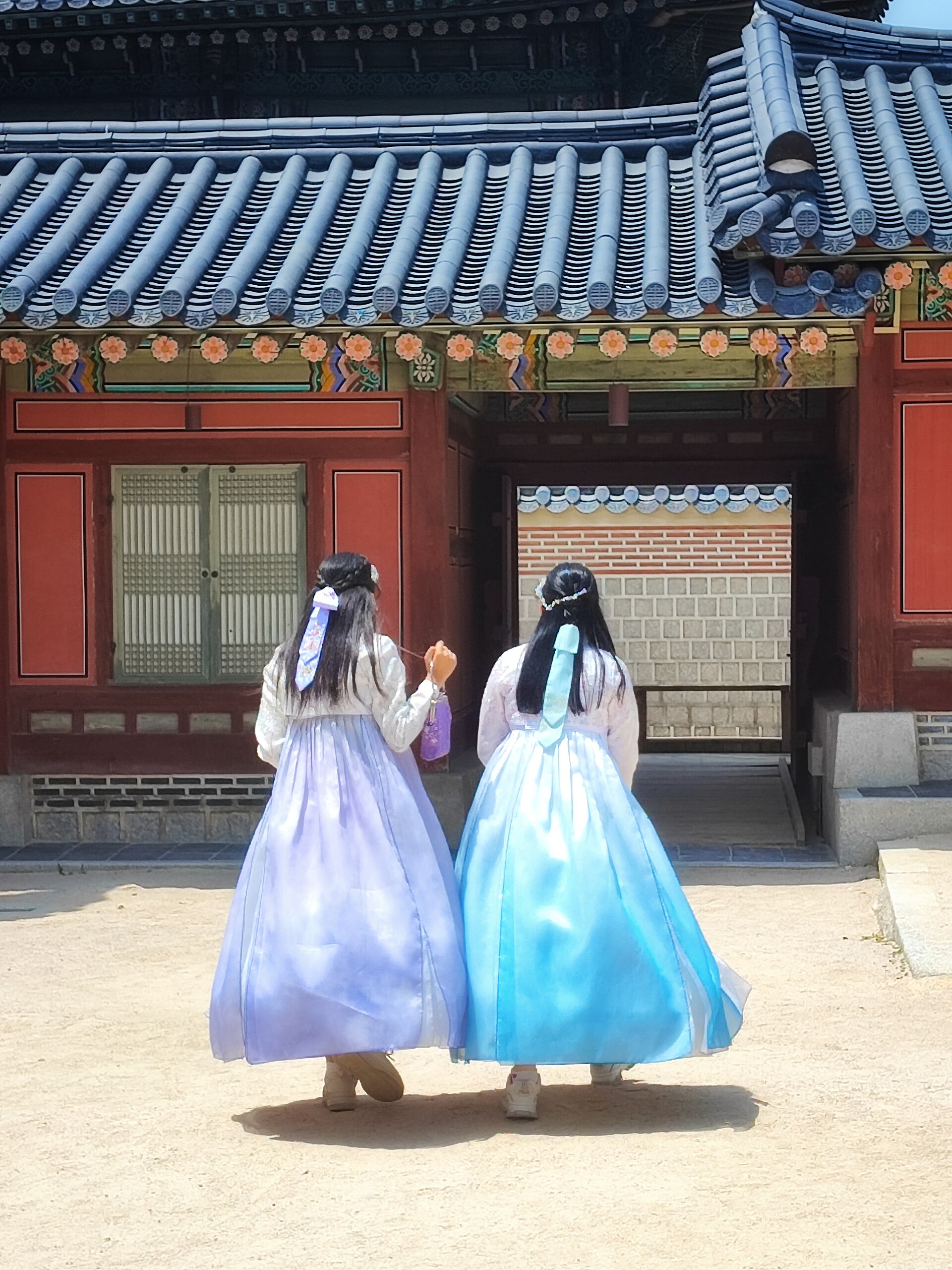 Two young women in colorful traditional hanbok walking near Gyeongbokgung Palace in Seoul