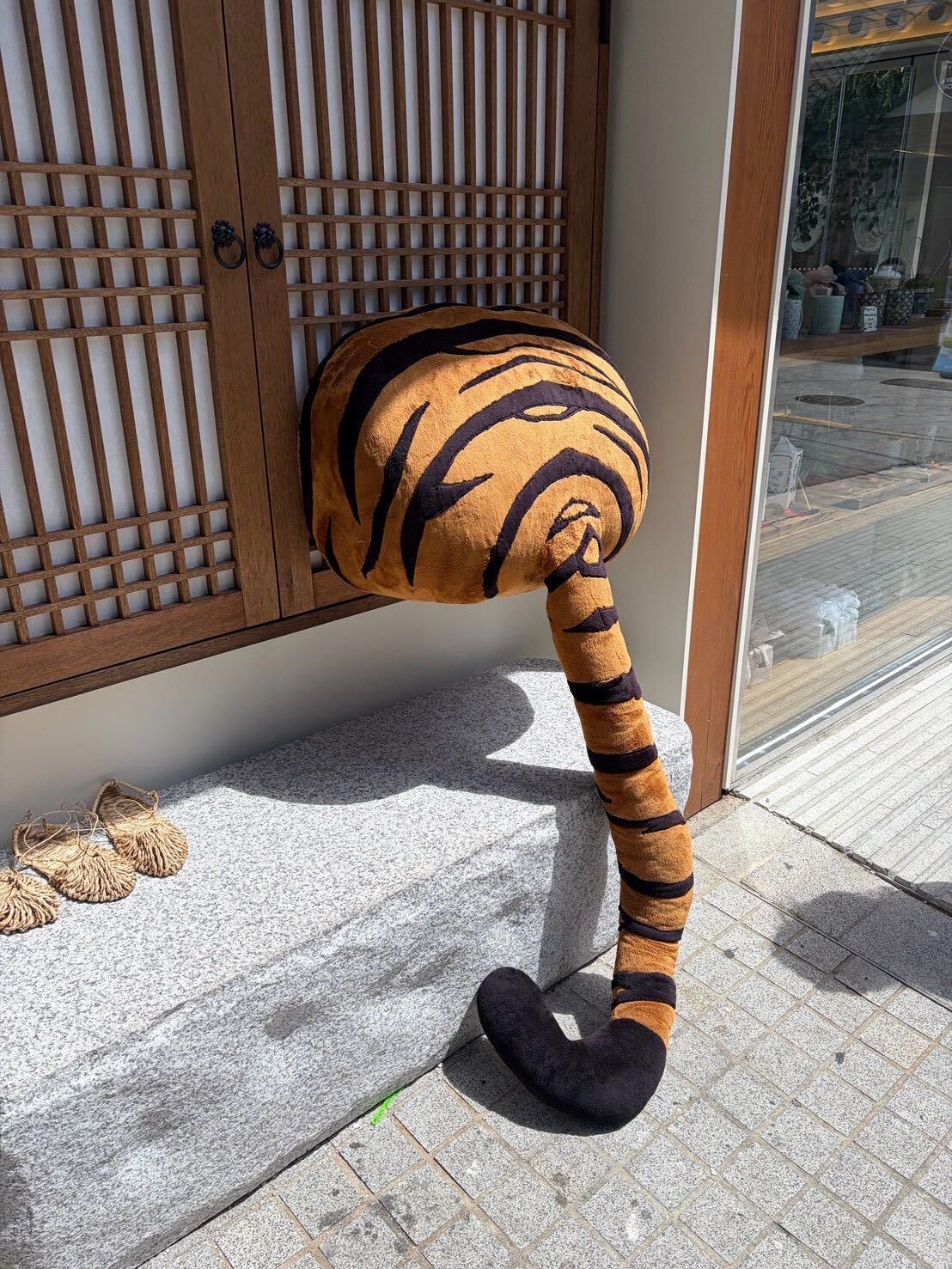 A plush tiger sculpture draped over a hanok doorway outside a cafe in Ikseon-dong