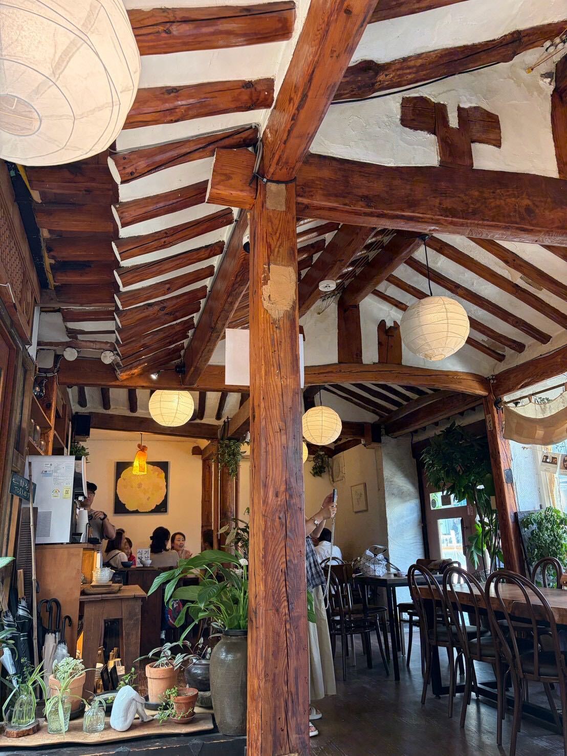 Tteuran's interior, exposed hanok roof beams and paper lanterns above the seating area