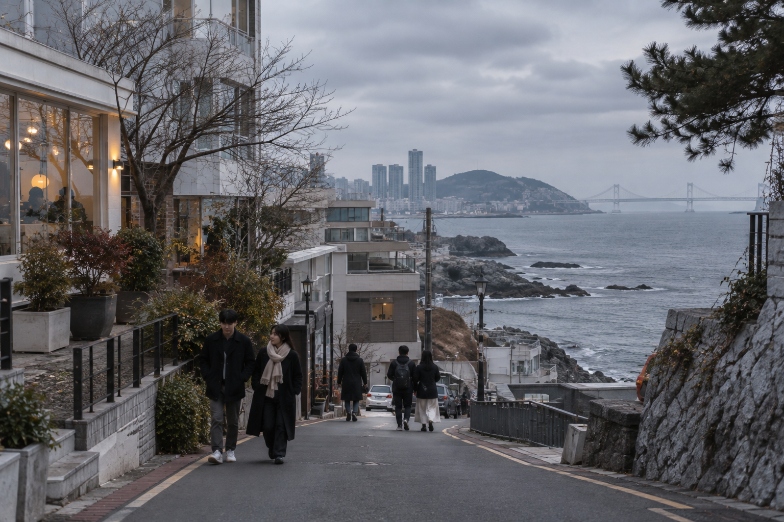A quiet Busan coastal street in late November with people in coats under cool grey light