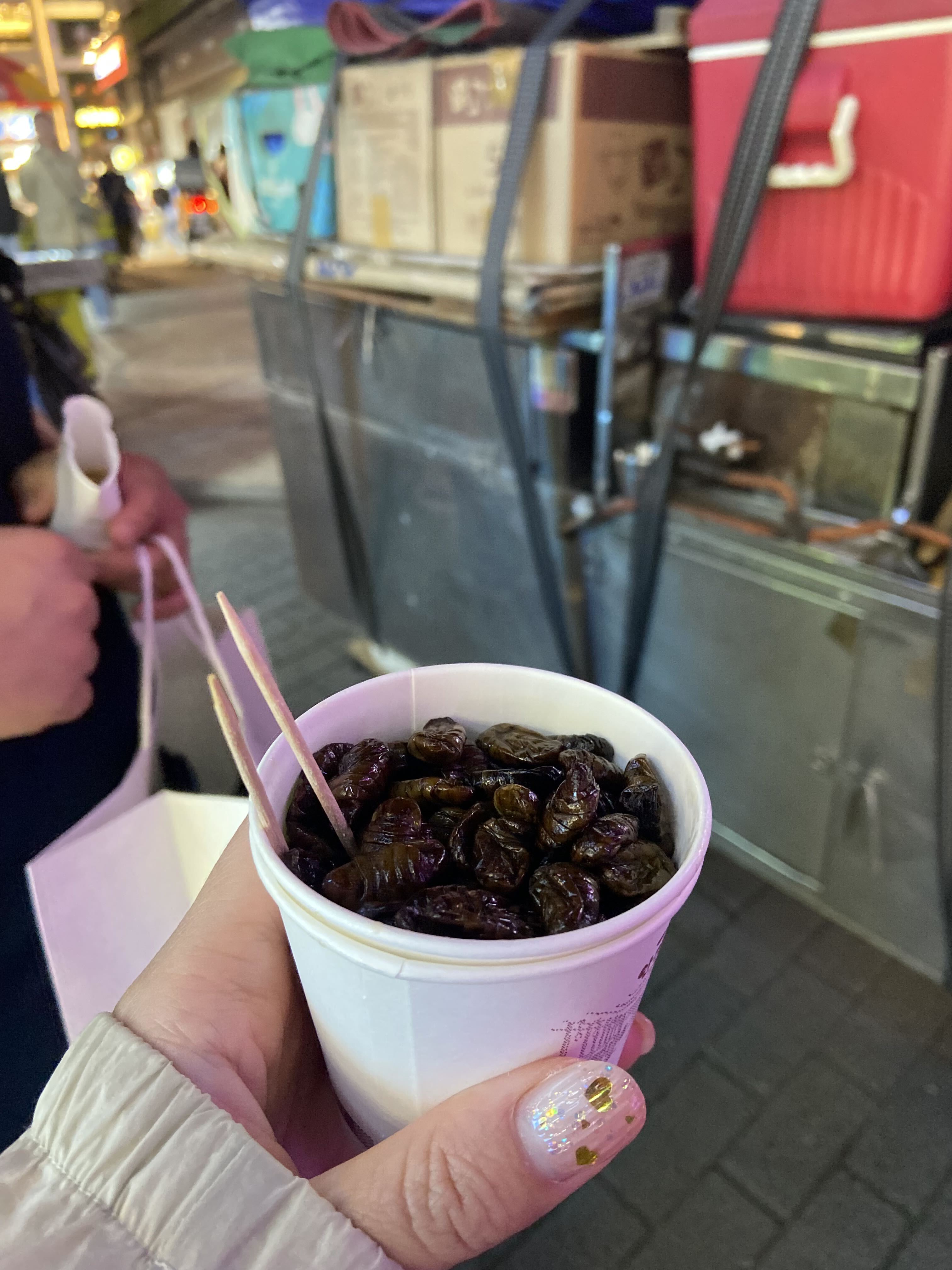 A paper cup filled with cooked Korean beondegi, or silkworm pupae
