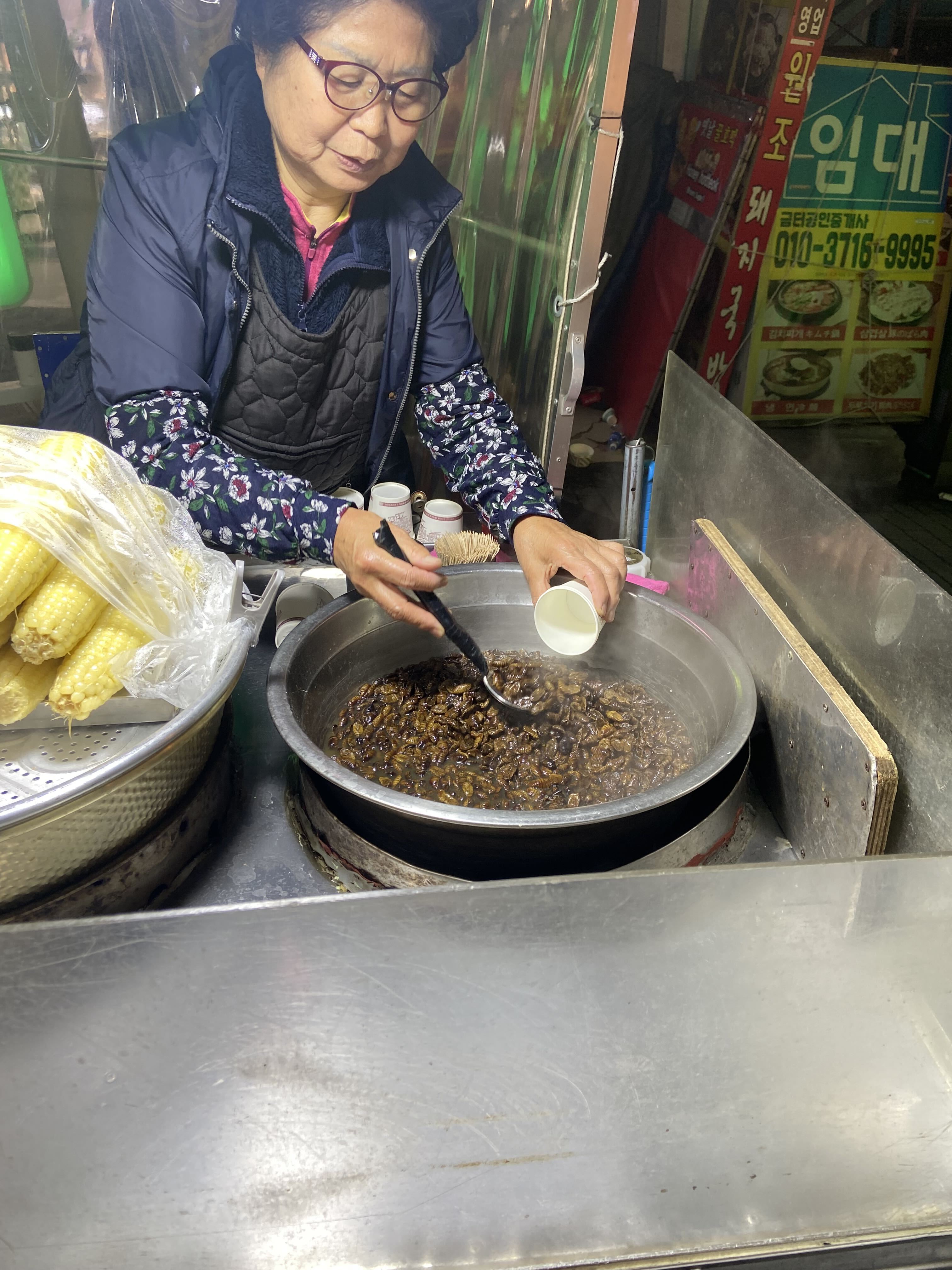 A Korean street-food vendor serving beondegi from a steaming pot