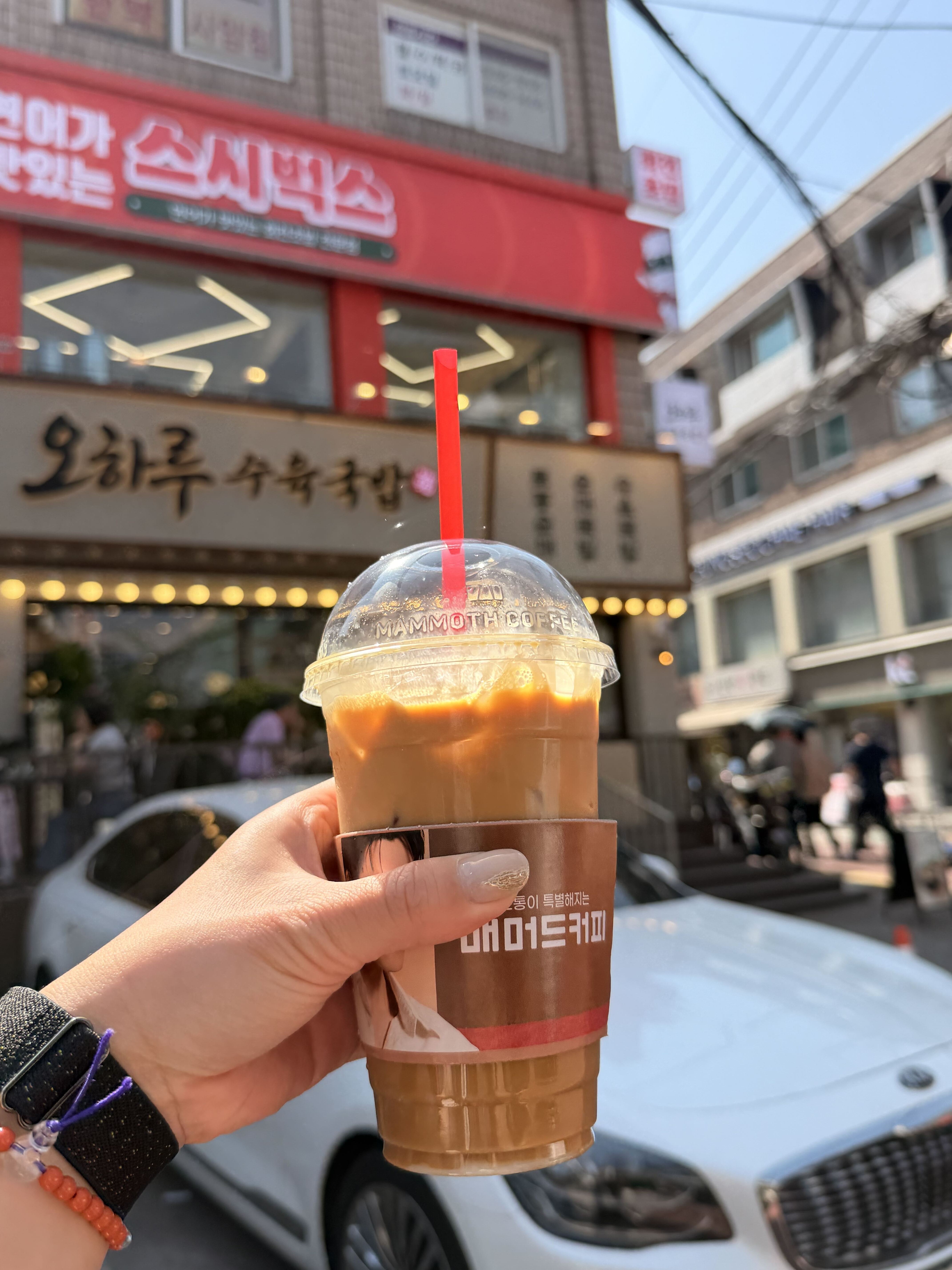 A banana milk coffee from a Korean coffee chain, held outside the café