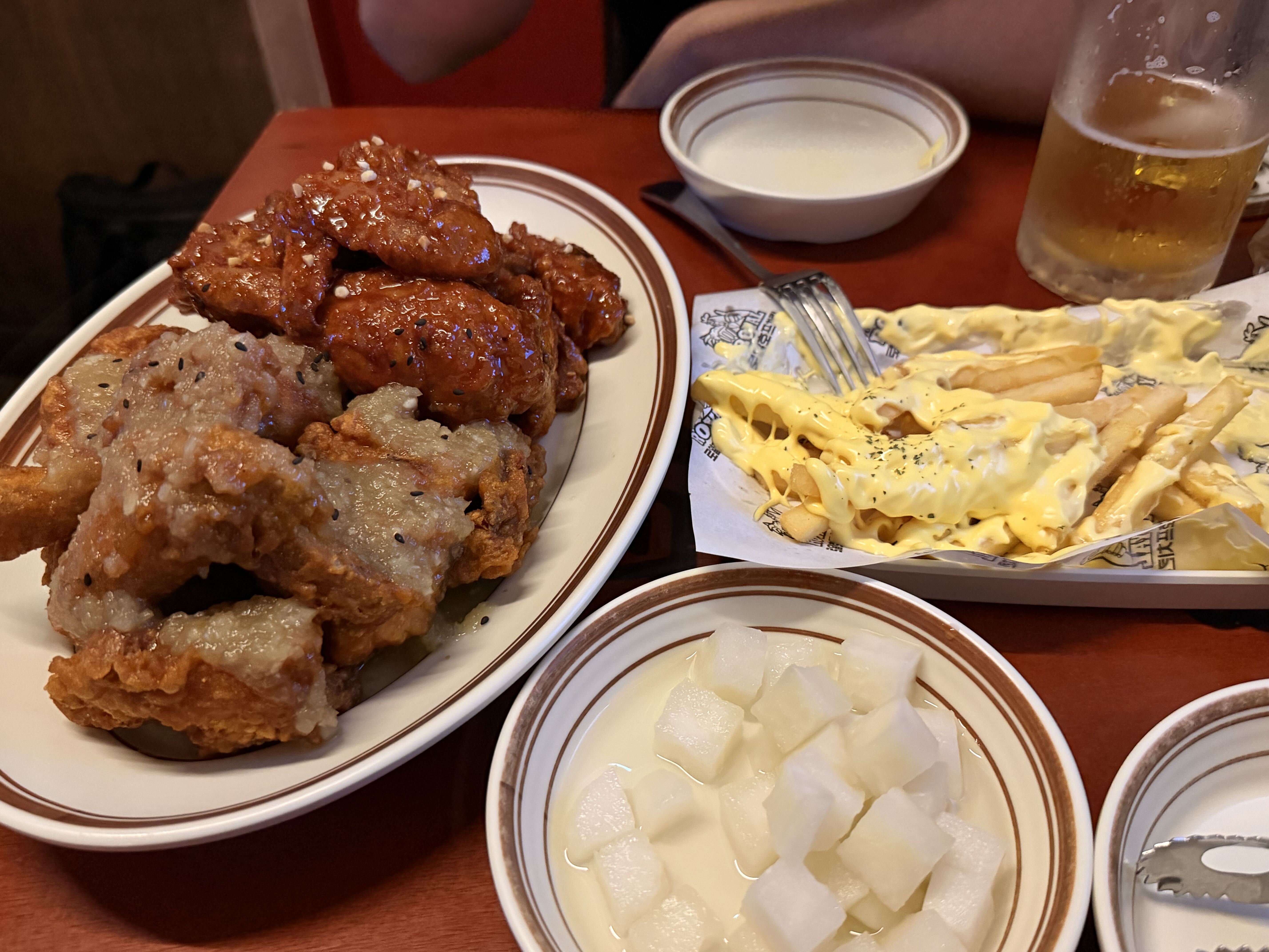 A table spread of Korean fried chicken in several flavours, including glazed and cheese-topped pieces