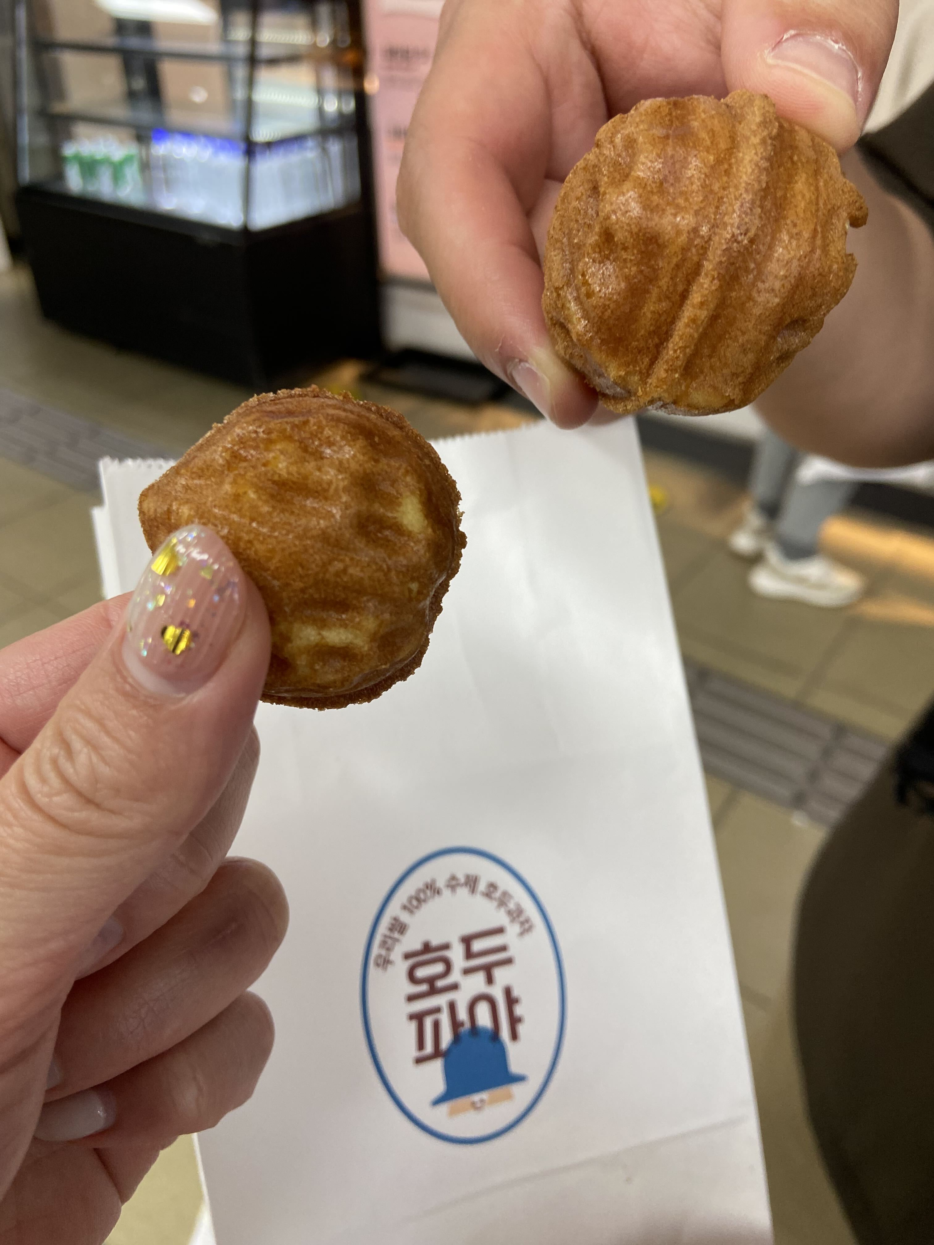 Freshly baked Korean hodu-gwaja walnut pastries being held in front of their box