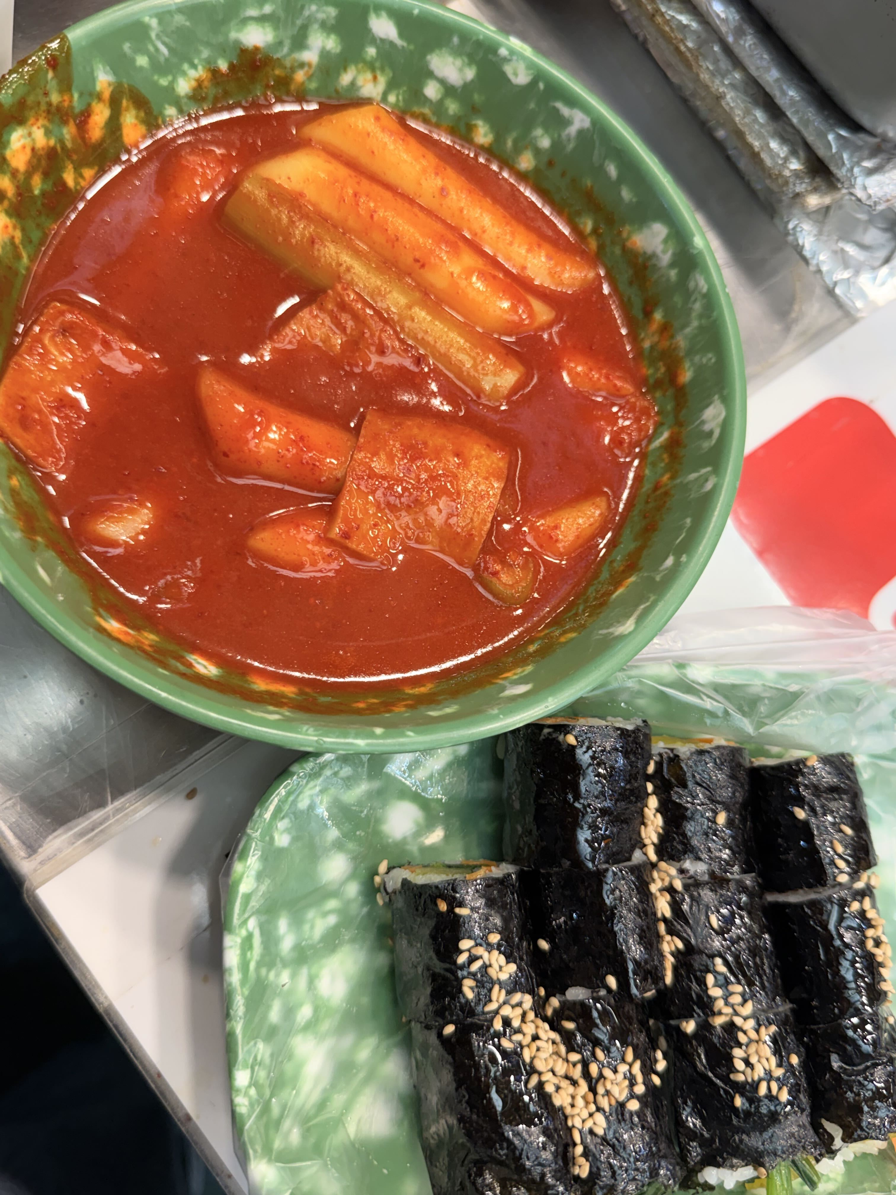 Tteokbokki sauce served beside sesame-topped seaweed rice rolls