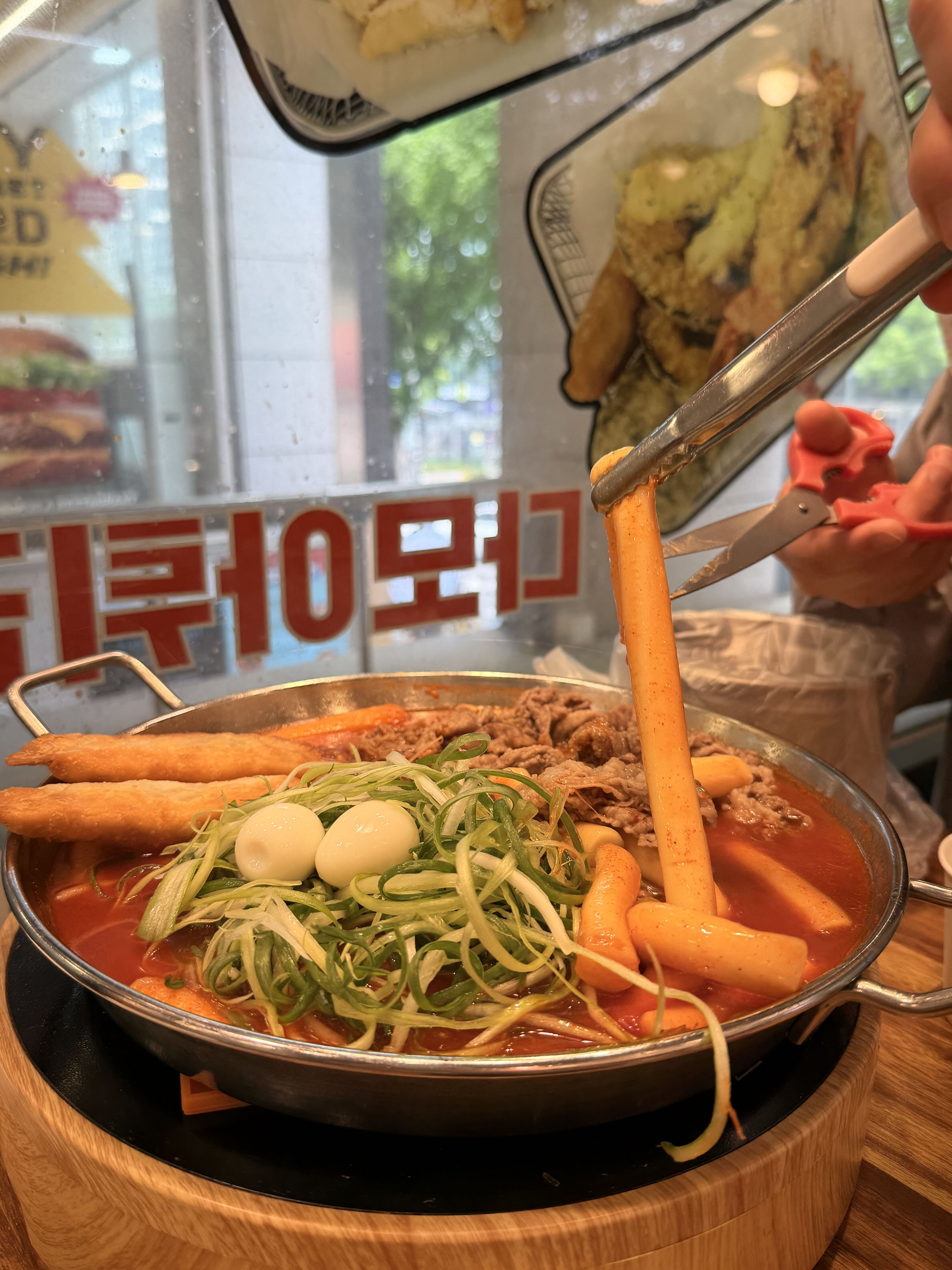 A bubbling pan of Korean tteokbokki with rice cakes, eggs and fish cakes at a street-food stall