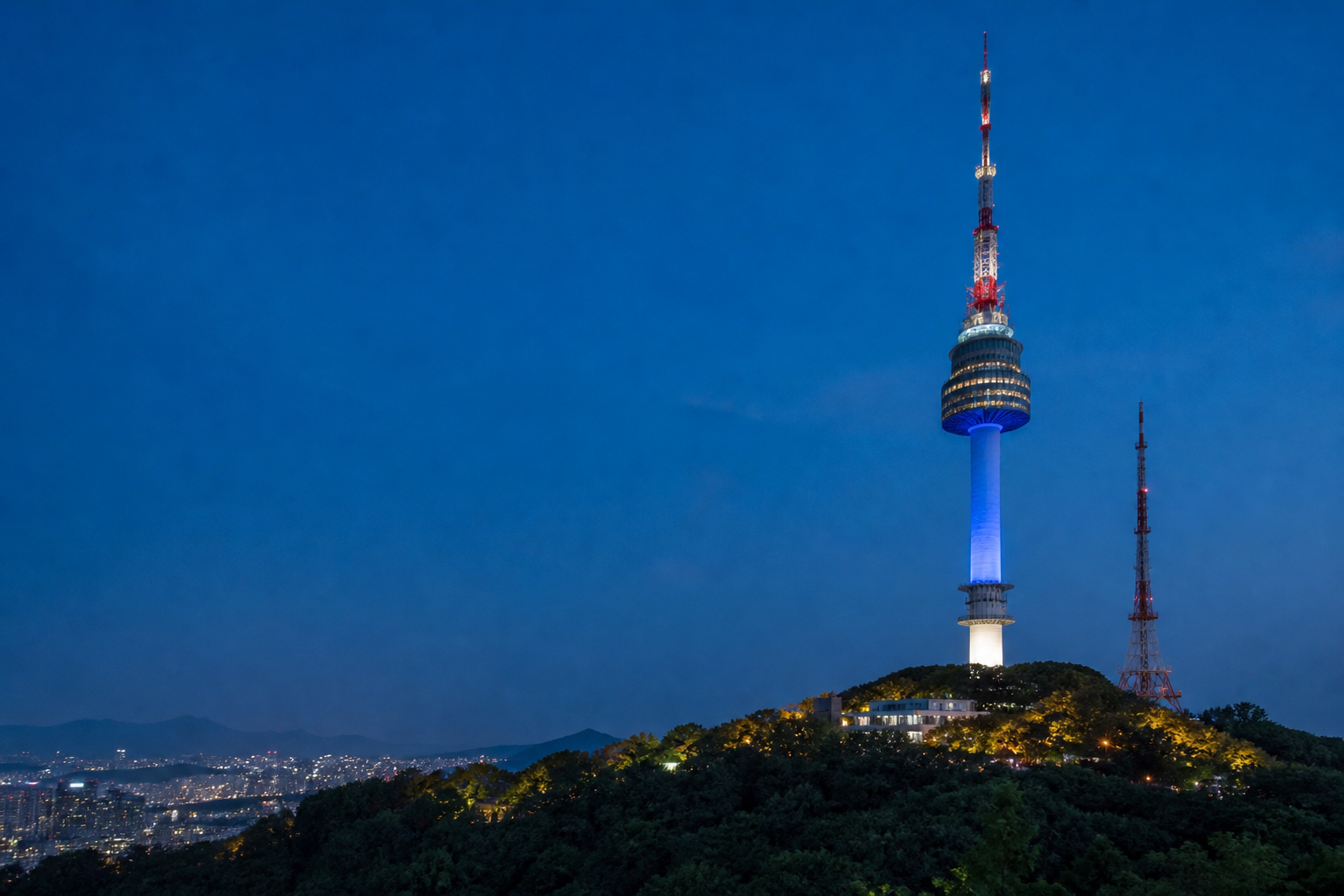 N Seoul Tower lit up at night on Namsan mountain, overlooking the city