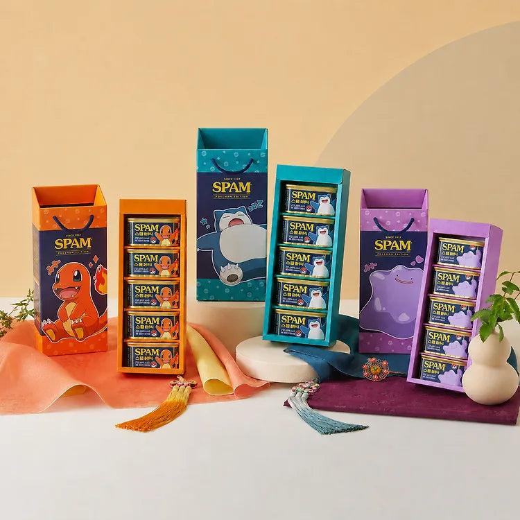 The three Pokémon SPAM Edition gift boxes side by side — orange Charmander, teal Snorlax, and purple Ditto — each with its own tasseled gift box and five-can tower