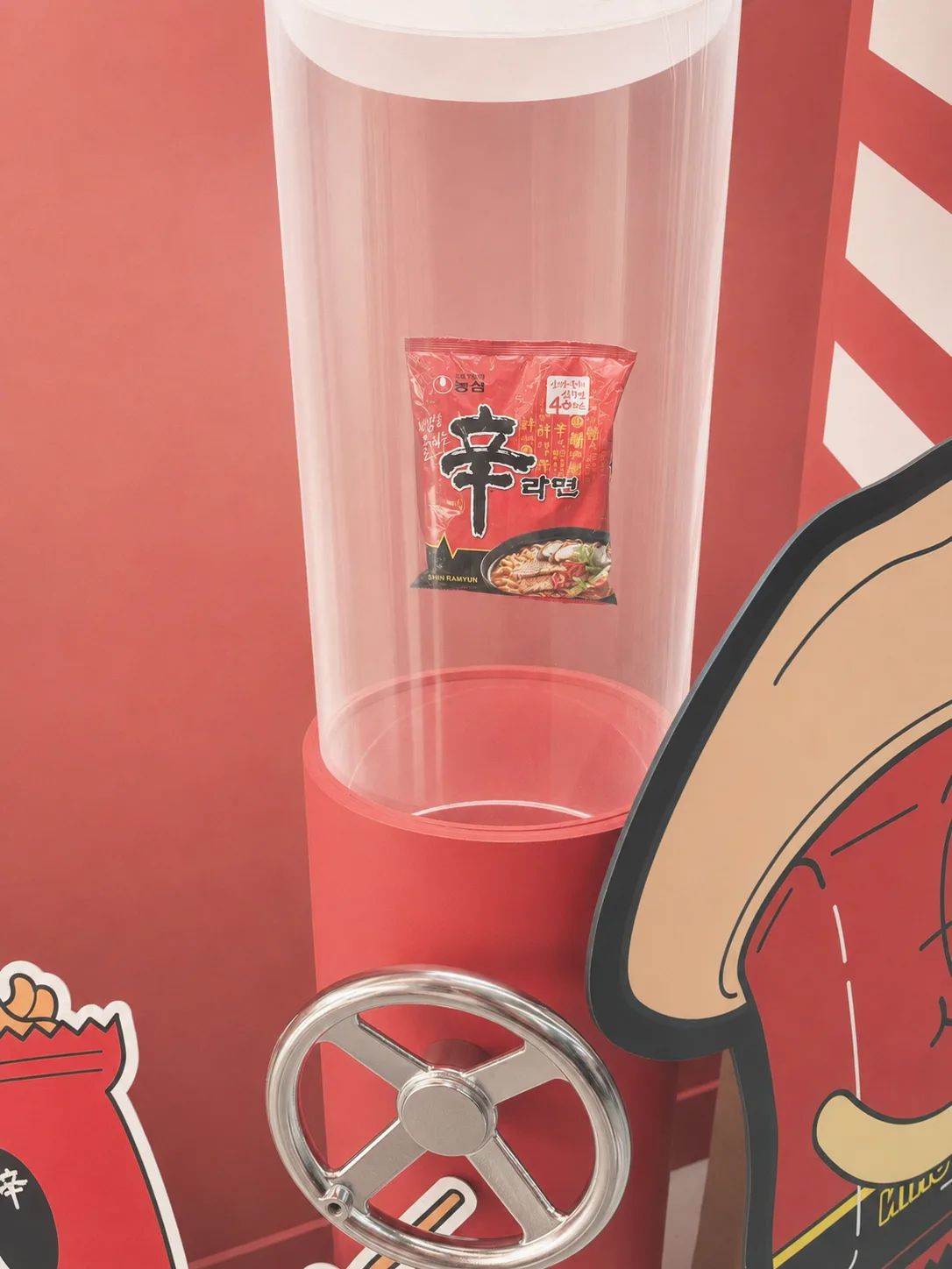 A single Shin Ramyun packet displayed inside a tall acrylic dispenser tube on the first floor