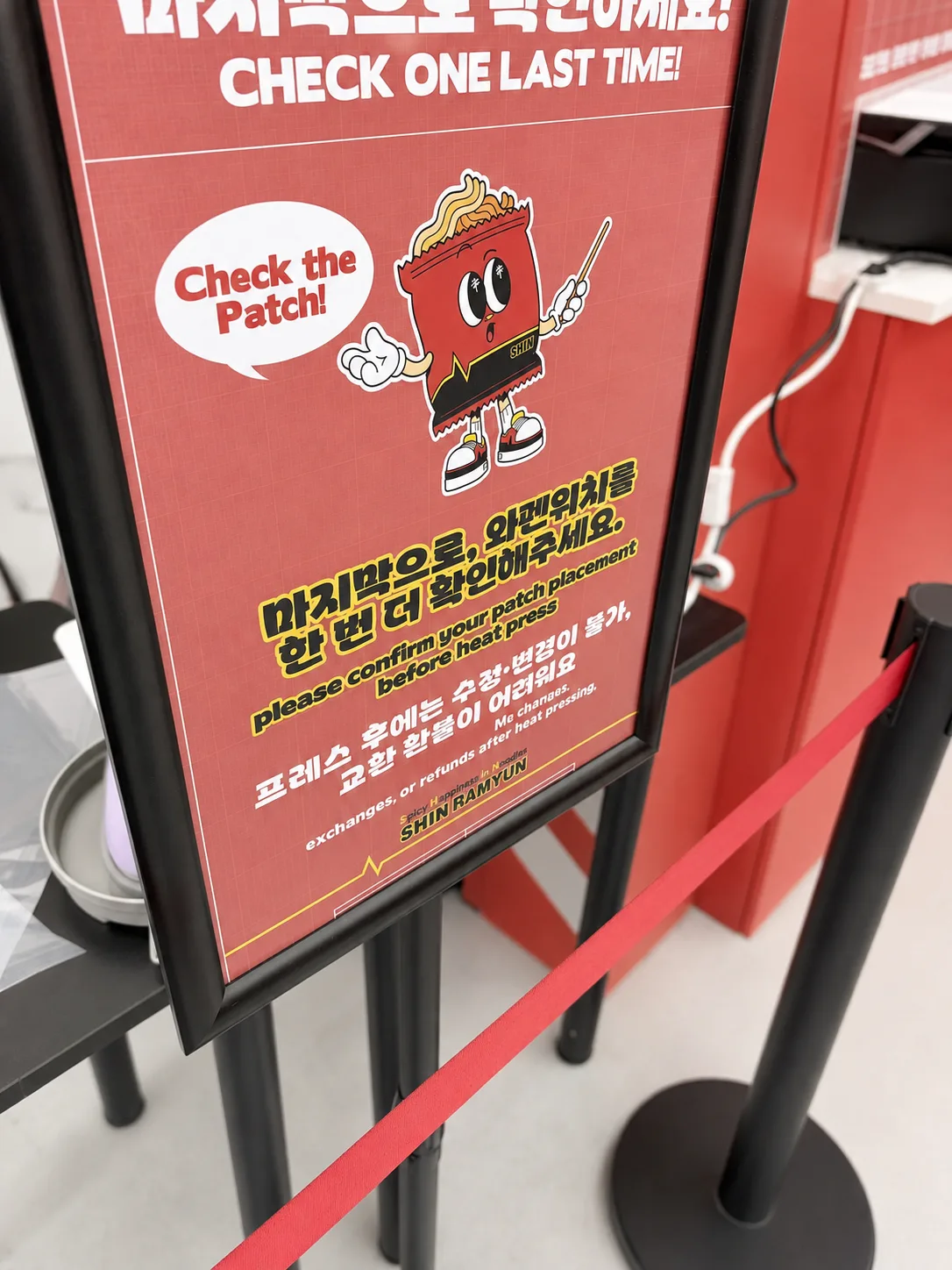 Signage at the patch station reading Check the Patch, warning that no changes or refunds are possible after heat pressing